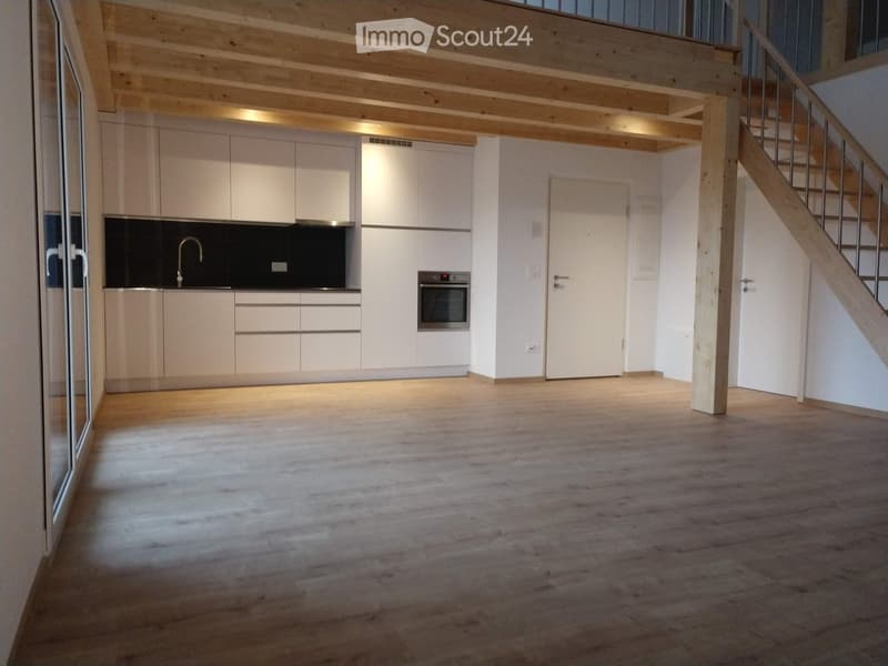 Modern kitchen with white cabinets, a sink, and an oven, featuring wooden flooring and exposed wooden beams on the ceiling.