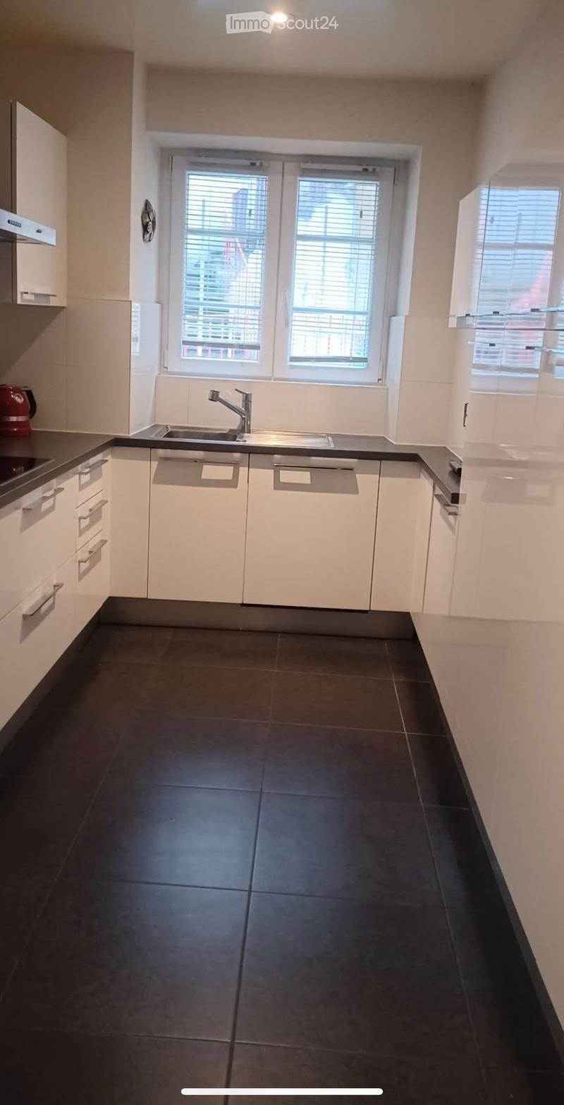 Modern kitchen with white cabinets, black countertops, and a dark tiled floor. Features a sink with a modern faucet and built-in drawers.