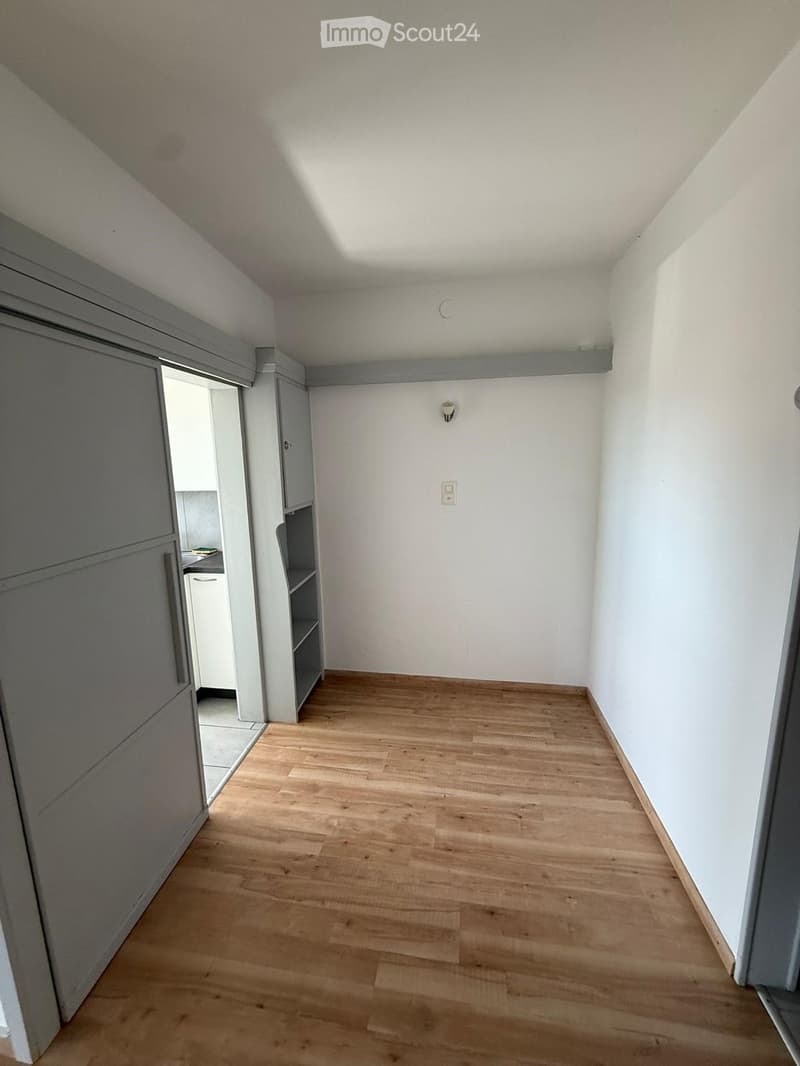 Empty room with light wooden flooring, white walls, and a small built-in shelf unit. No furniture or personal items are present.