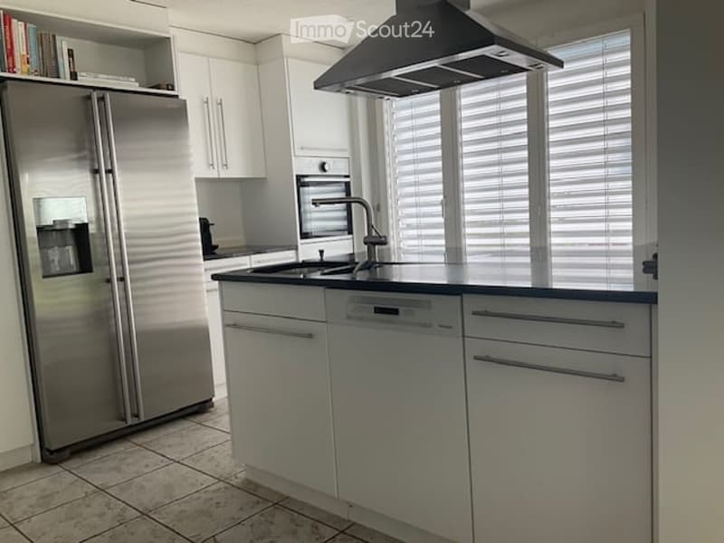 Modern kitchen with white cabinets, stainless steel appliances, and a large island with a sink and faucet.