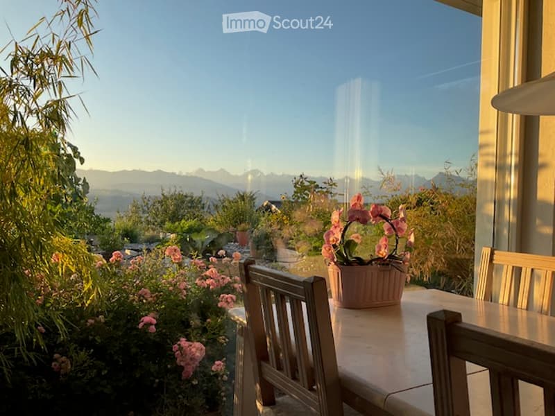 Balcony with wooden railings, potted plants, and a scenic view of a lake and mountains.