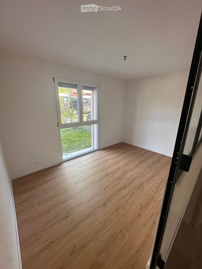 Empty room with wooden flooring, white walls, and a large sliding glass door leading to an outdoor area.