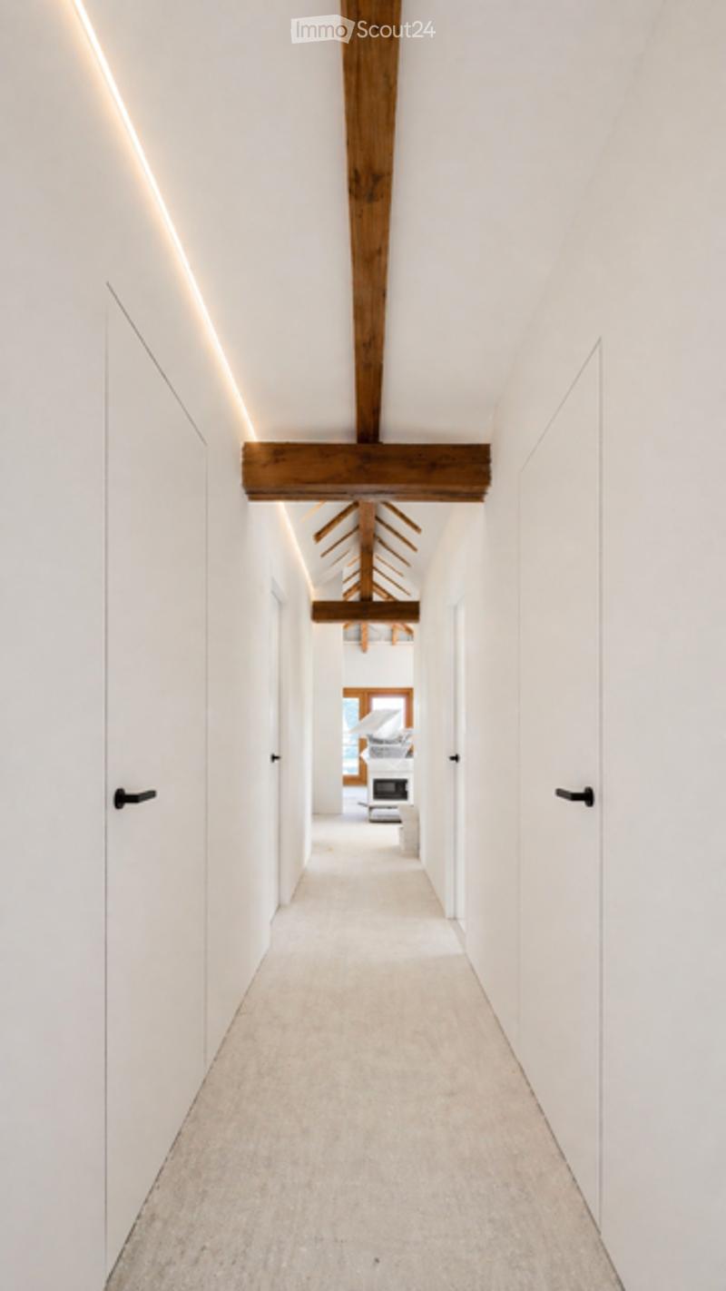 Modern hallway with white walls, wooden ceiling beams, recessed lighting, and a view into a living room area.