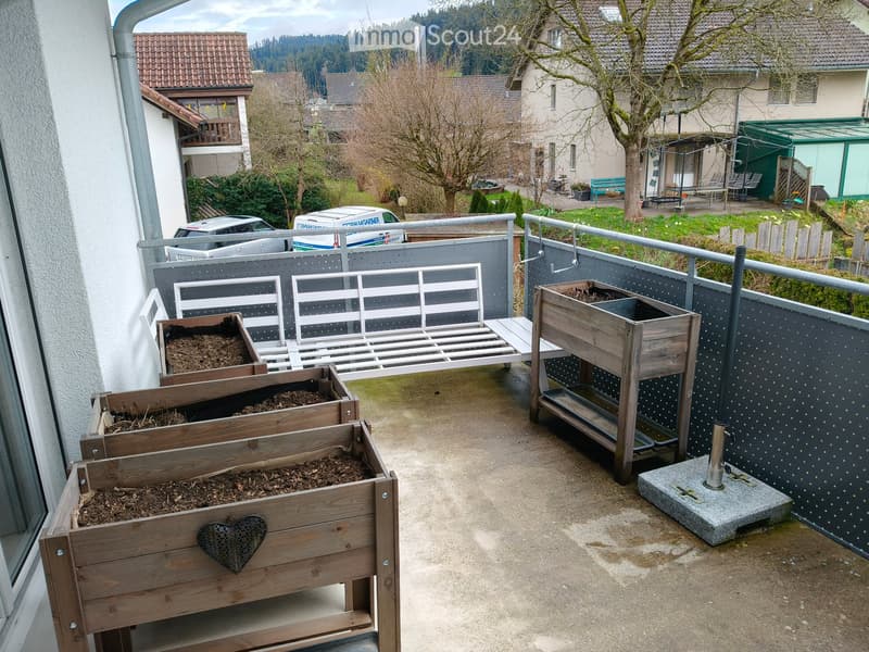 Balcony with wooden planters, metal railing, and a view of the surrounding neighborhood.