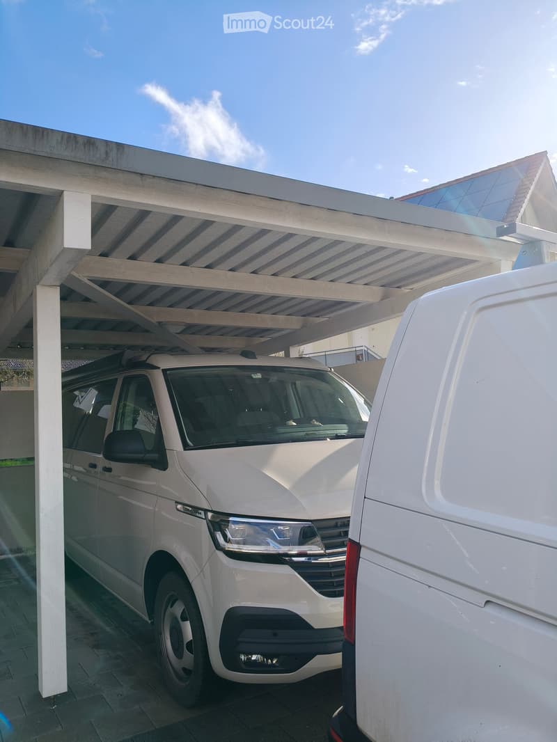 Garage with two vans parked under a covered structure, white walls, and a modern design.