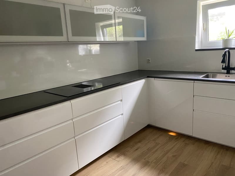 Modern kitchen with white cabinets, black countertop, and stainless steel sink.