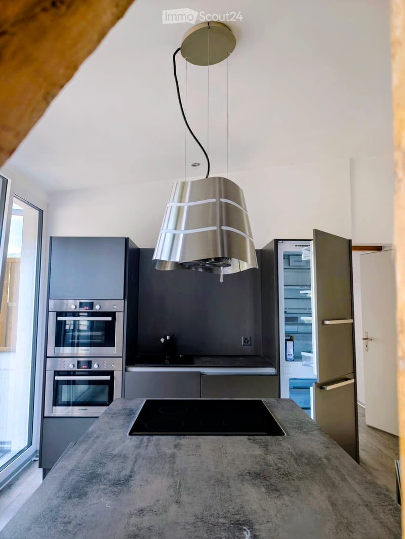 Modern kitchen with grey cabinets, stainless steel appliances, and a central island with an induction cooktop.