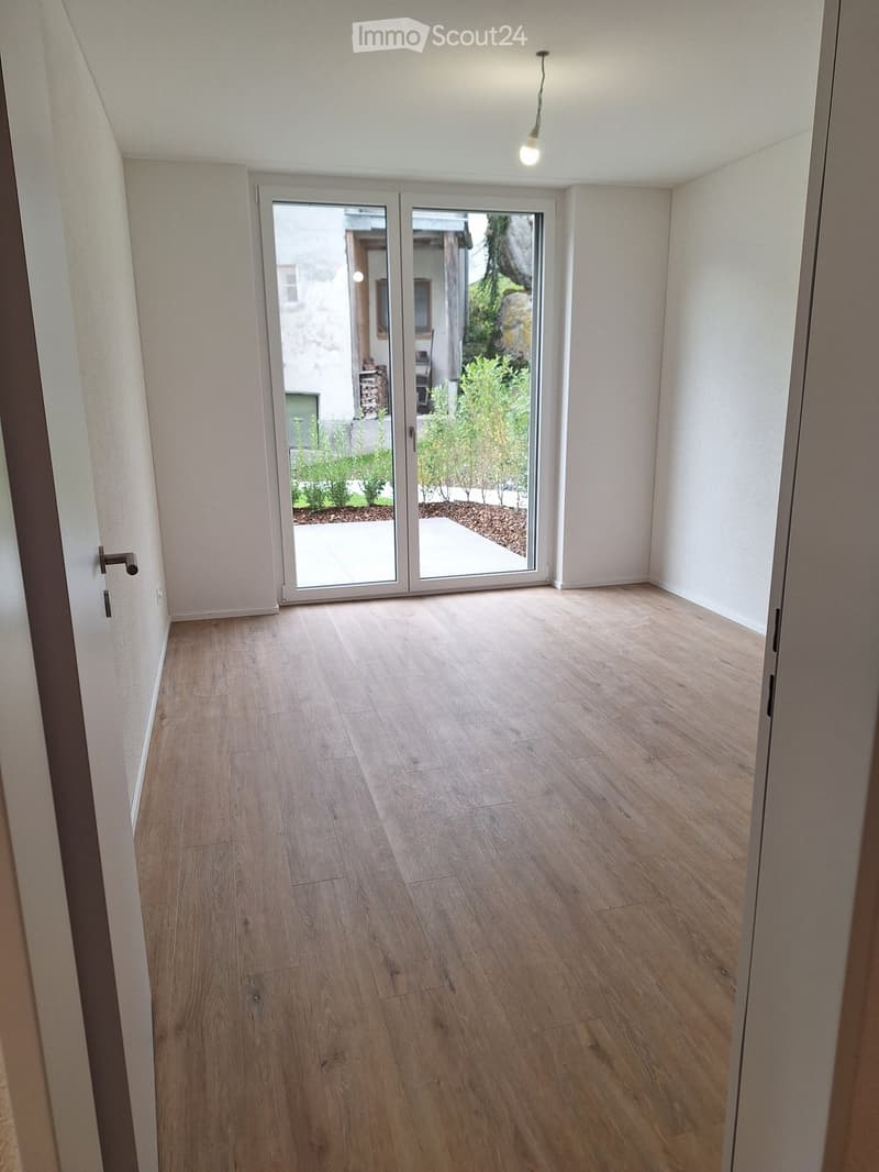 empty room, wooden floor, sliding glass doors, balcony, outdoor plants, white walls, door