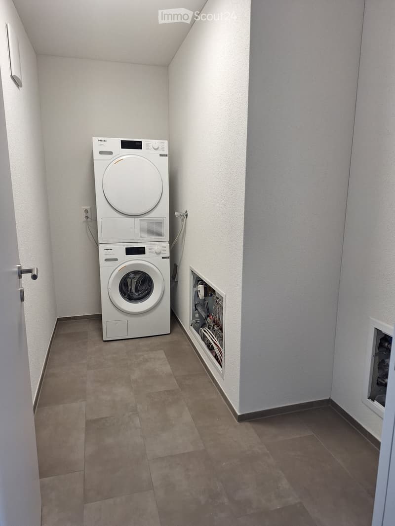 Tiled floor, white walls, stackable washer and dryer, electrical panel on wall