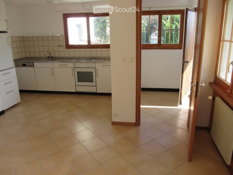 Bright kitchen with white cabinets, a refrigerator, dishwasher, and oven. The space features tiled flooring and large windows allowing natural light to enter.