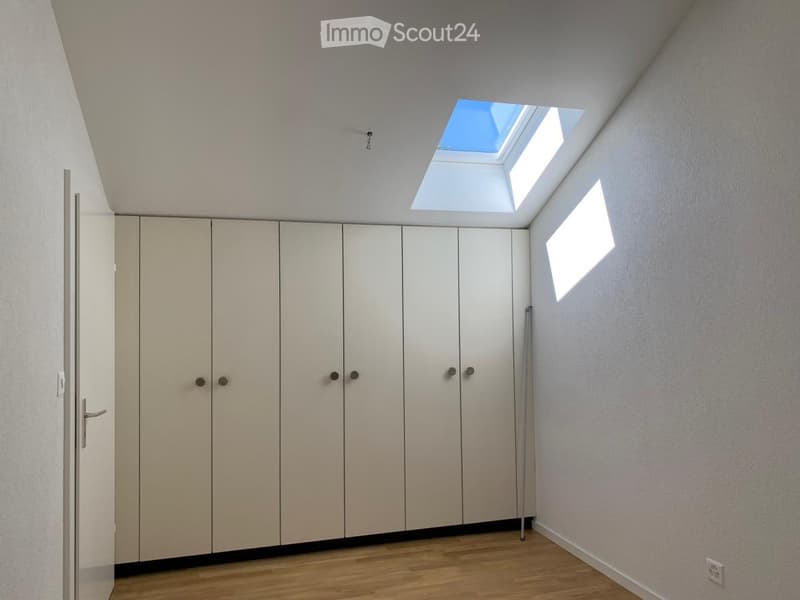 Empty room with light-colored walls, wooden flooring, built-in wardrobes, and a skylight window allowing natural light.