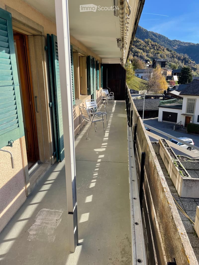 Balcony with a scenic mountain view, featuring a few chairs and a railing.