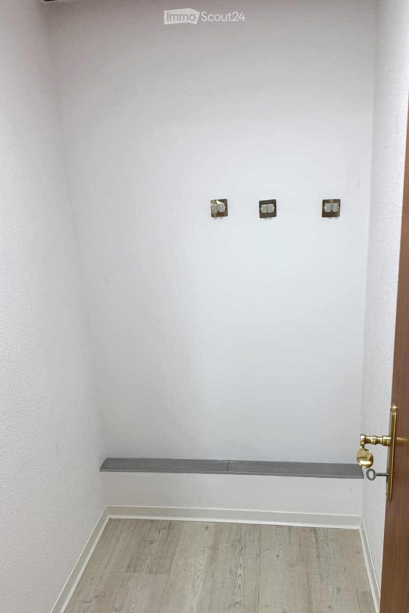 Empty room with light wooden flooring, white walls, and a single shelf mounted on the wall. No furniture or equipment is present.
