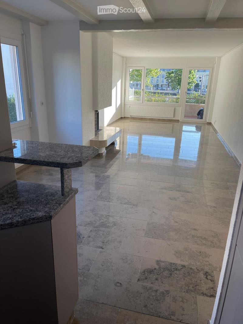 Empty room with tiled floor, large windows, and a small counter area. No furniture or equipment visible.