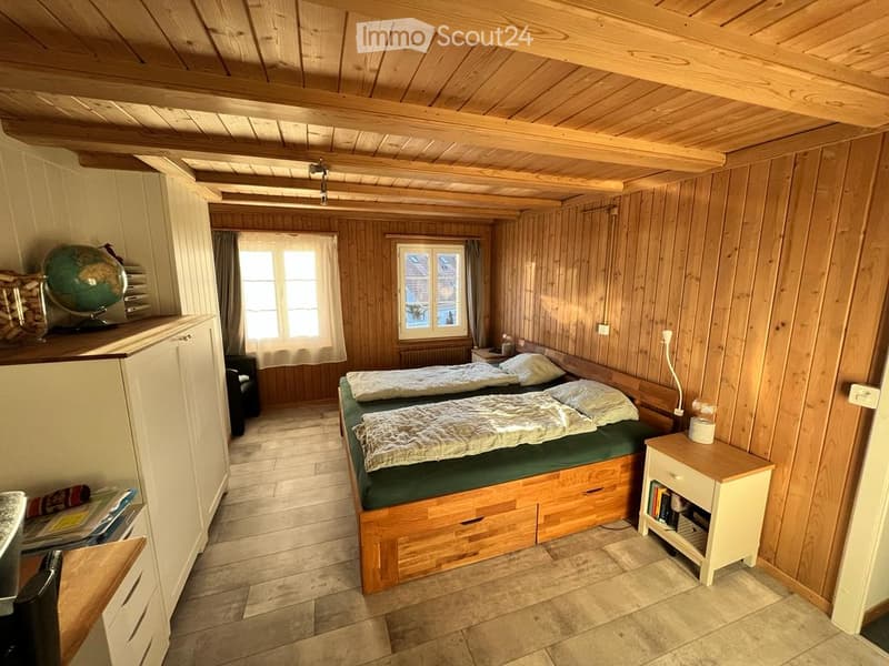 Cozy wooden bedroom with two single beds, nightstand, globe, and wooden furniture.