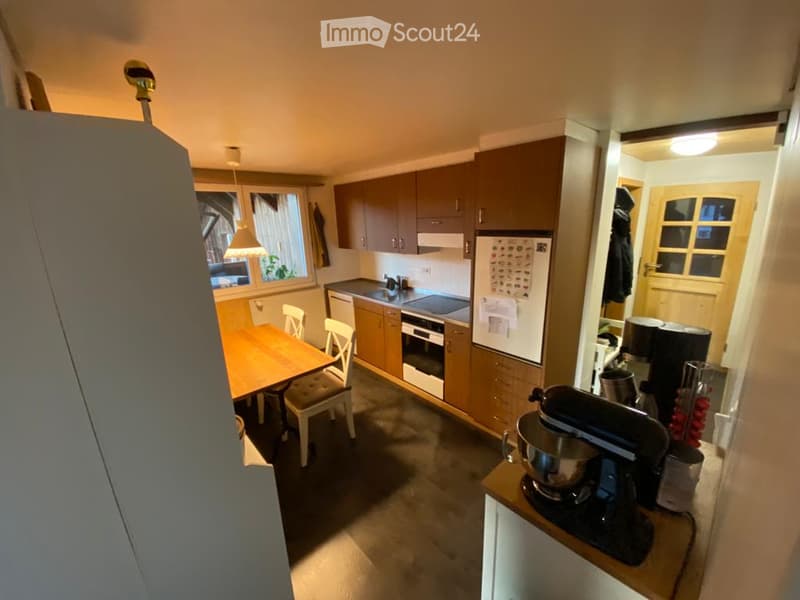 Modern kitchen with wooden cabinets, stainless steel appliances, a dining table with chairs, and a mixer on the counter.