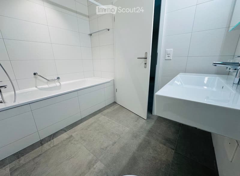 modern bathroom with white tiles, bathtub, sink, and shower