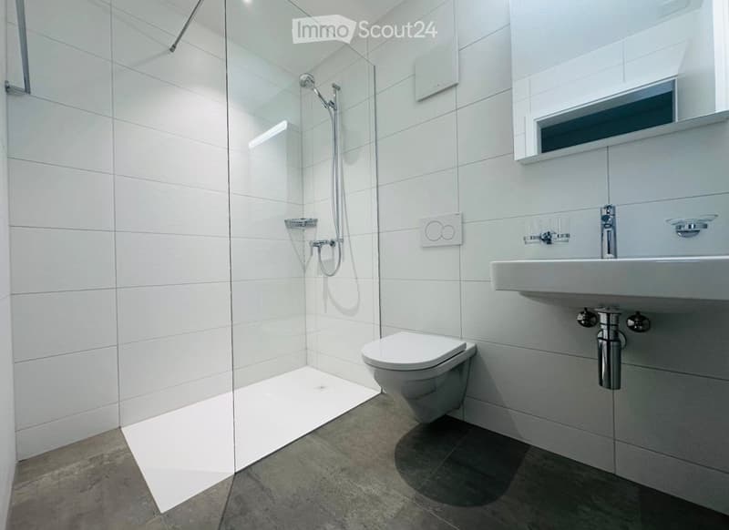 modern bathroom with white tiles, glass shower enclosure, white toilet, white sink, silver faucets