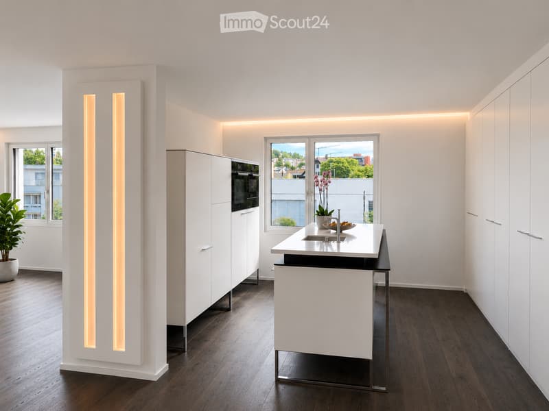 Modern kitchen with white cabinets, a central island, and a sink. Features include wooden flooring, large windows with a view, and built-in lighting.
