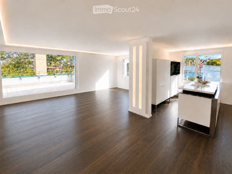 Modern kitchen with dark hardwood flooring, white cabinetry, and a central island with a sink and faucet. Large windows offer a view of a balcony area.