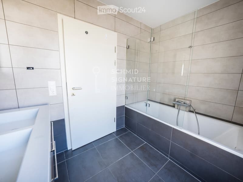 Modern bathroom with a bathtub, glass-enclosed shower, and white cabinetry.