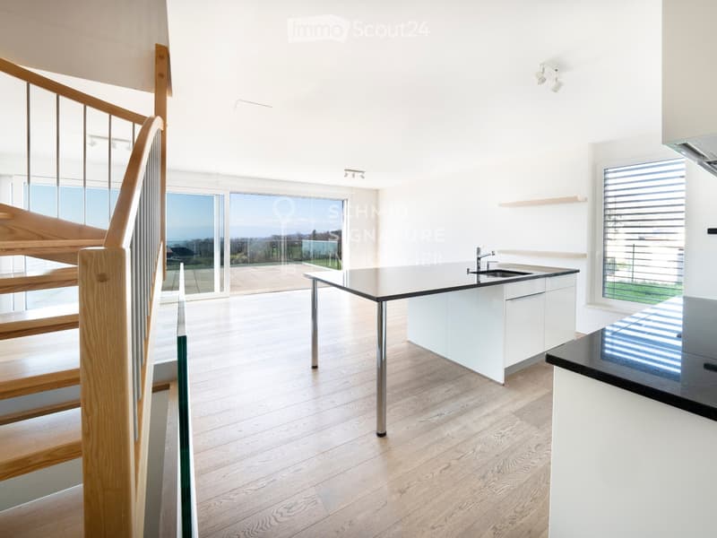 Modern kitchen with white cabinets, a central island, and large windows overlooking the outdoor area.