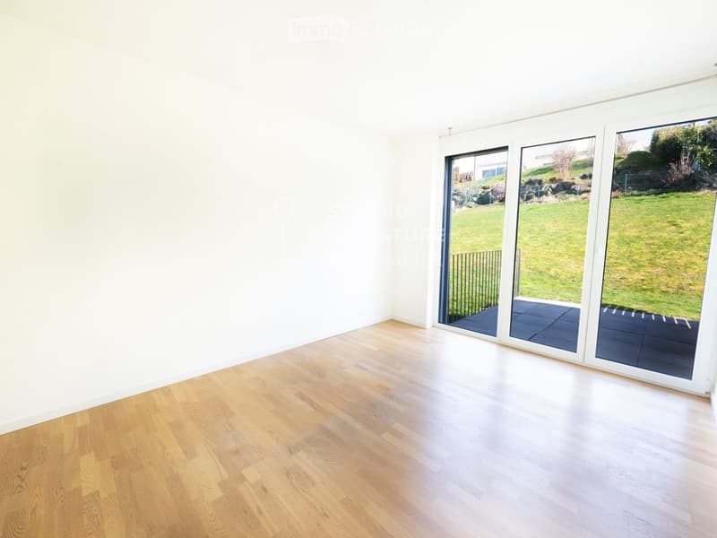 Empty room with light wooden flooring and large sliding glass doors leading to a grassy outdoor area.