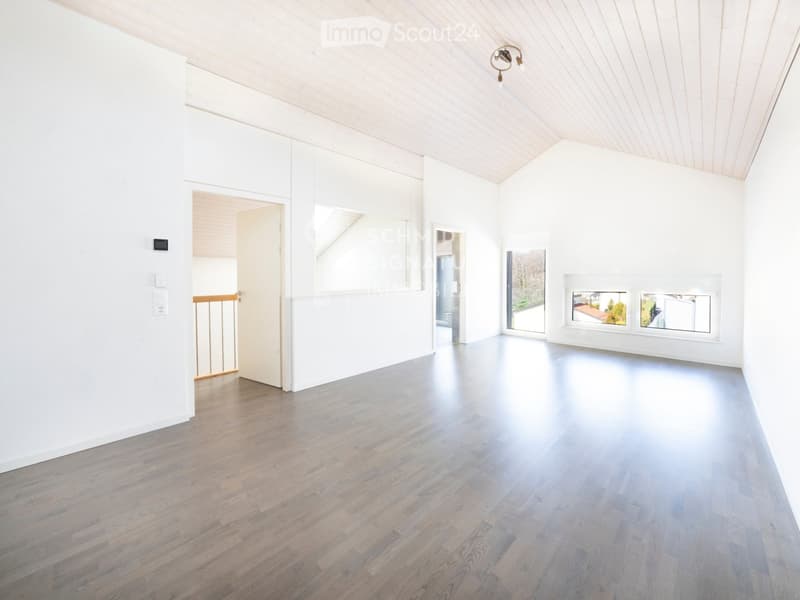 Empty room with white walls, wooden floor, and large windows. No furniture or equipment visible.