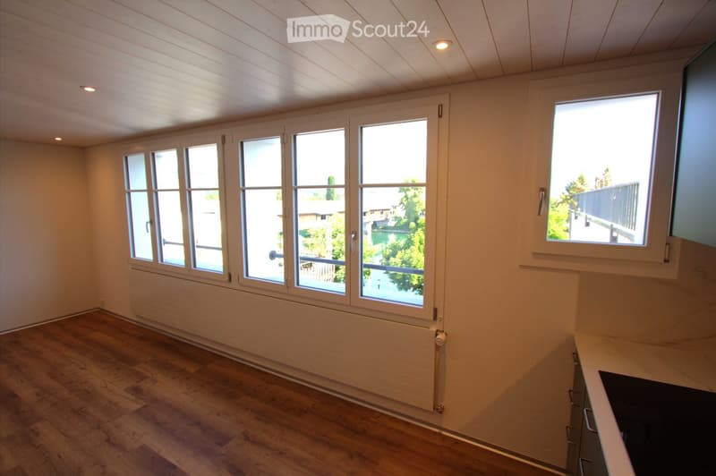 Empty room with wooden flooring, large windows, and white walls. No furniture or equipment present.
