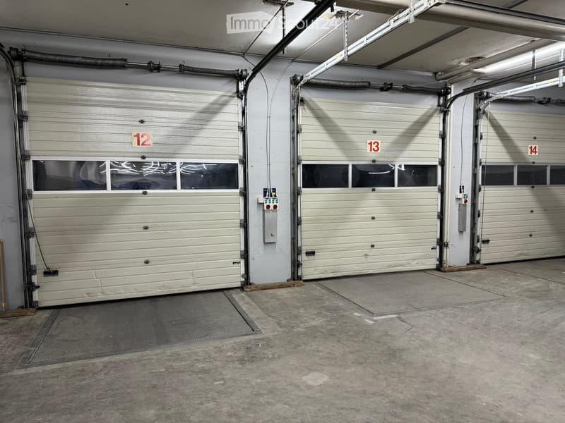 Three garage doors, concrete flooring, industrial setting, gray metal doors