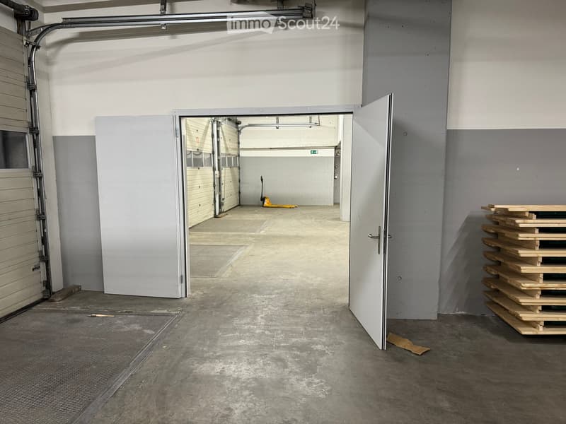 empty garage with a white door, concrete floor, grey walls, stack of wooden pallets