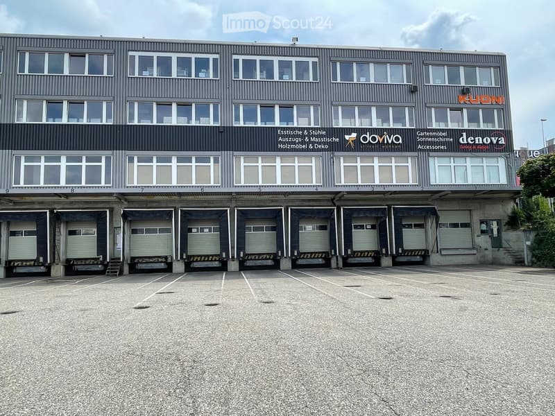 Grey facade, large windows, 6 parking spaces, signage for Doviva, Gartenmodell, and Deneva