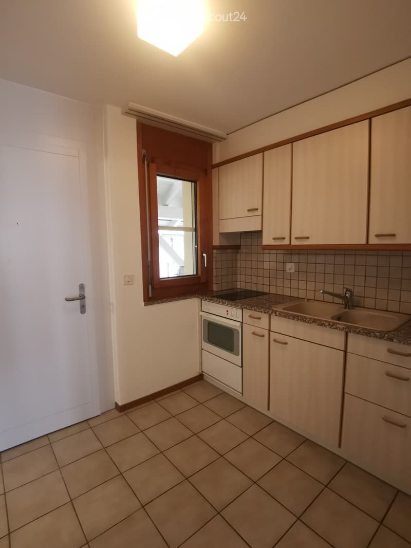 Modern kitchen with tiled floor, white cabinets, built-in oven, sink, and window.