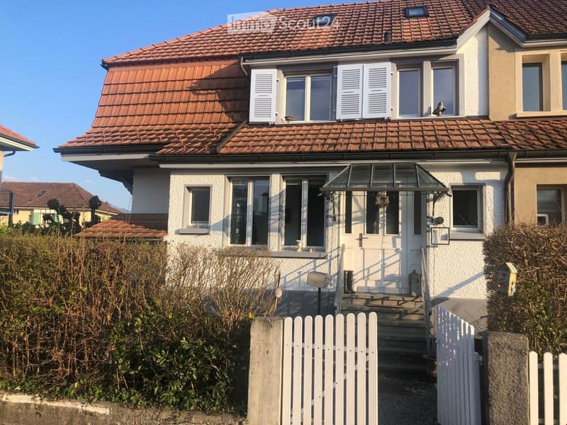 Two-story house with red-tiled roof, white exterior, multiple windows, and a small porch with a glass roof.