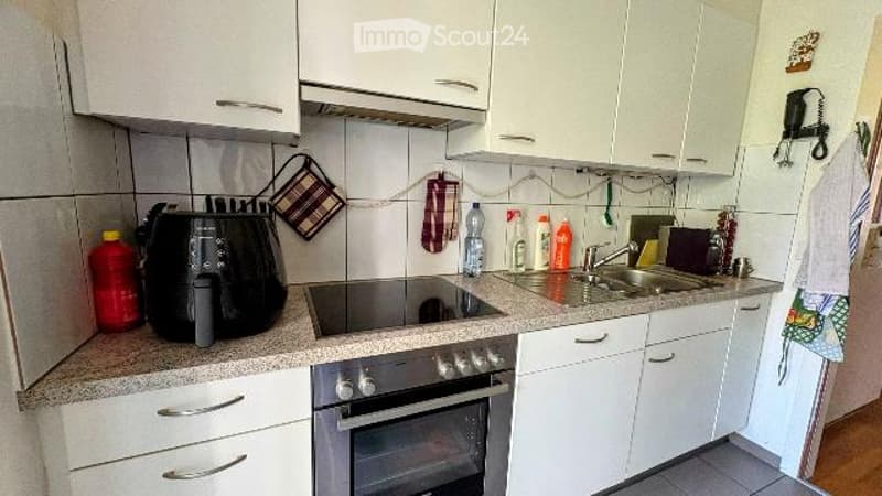 Modern kitchen with white cabinets, granite countertop, stainless steel oven, fryer, and sink.