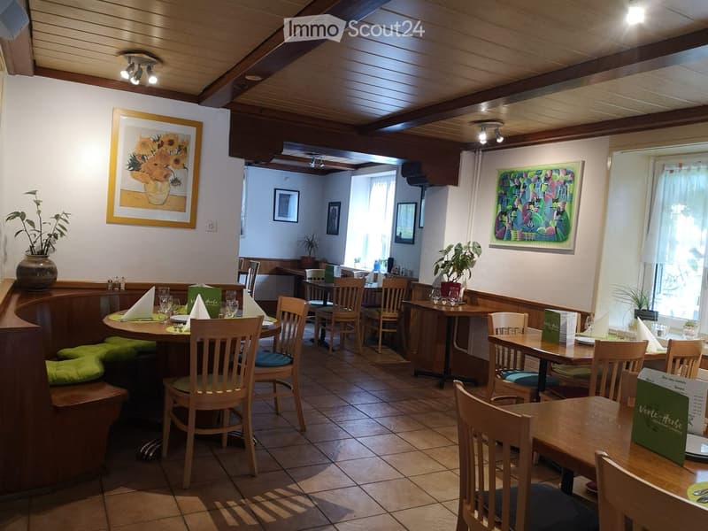 Restaurant interior with wooden tables, chairs, menus, and decorative vases and artwork.