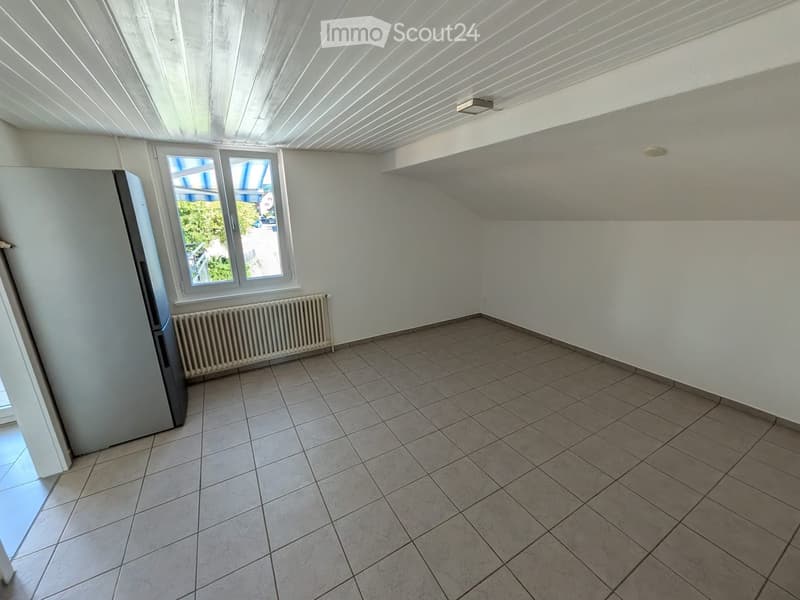 Empty room with tiled floor, white walls, window with view, radiator, and built-in shelving on one wall.