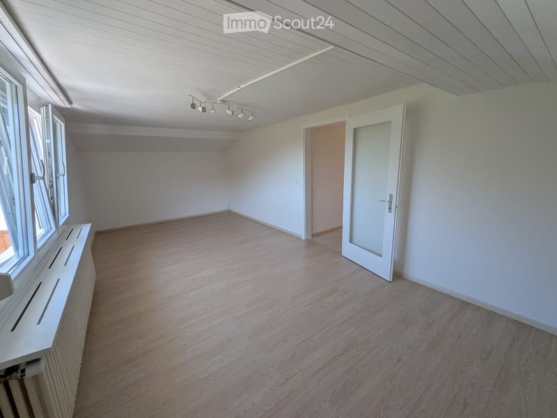 Empty room with wooden flooring, white walls, large windows, and a white radiator. No furniture or equipment present.