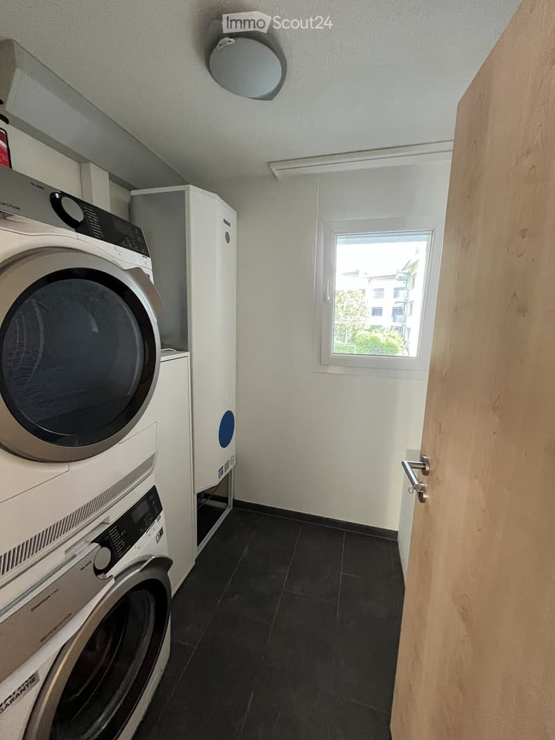 Bathroom with black tiled floor, white walls, and a window. Contains a washing machine and a dishwasher.