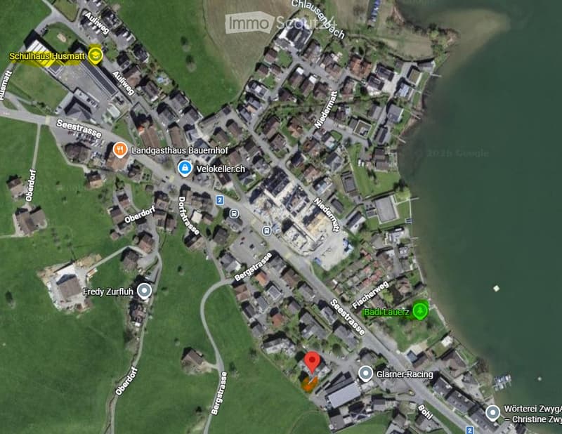 Aerial view of a residential area with multiple buildings, streets, and green spaces. The map shows labeled streets, buildings, and landmarks such as 'Schulhaus I-Usmatt' and 'Landgasthaus Bauernhof'.