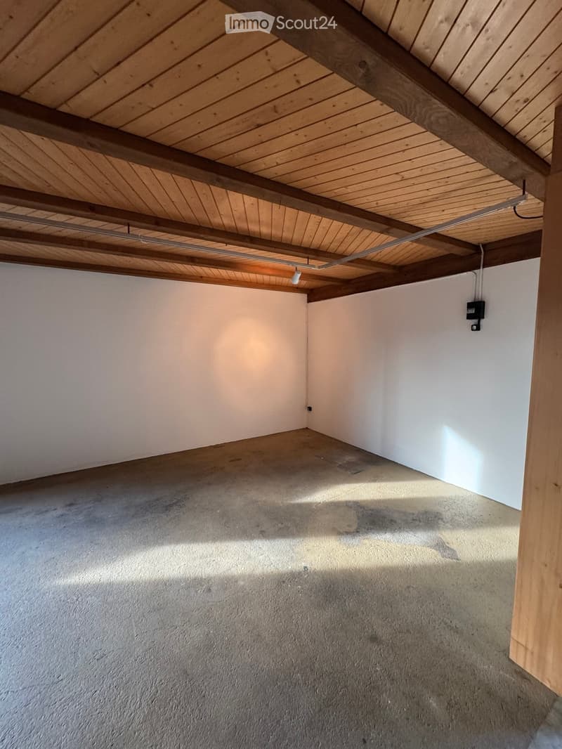 Empty room with exposed wooden beams on the ceiling, concrete floor, and white walls. No furniture or equipment present.