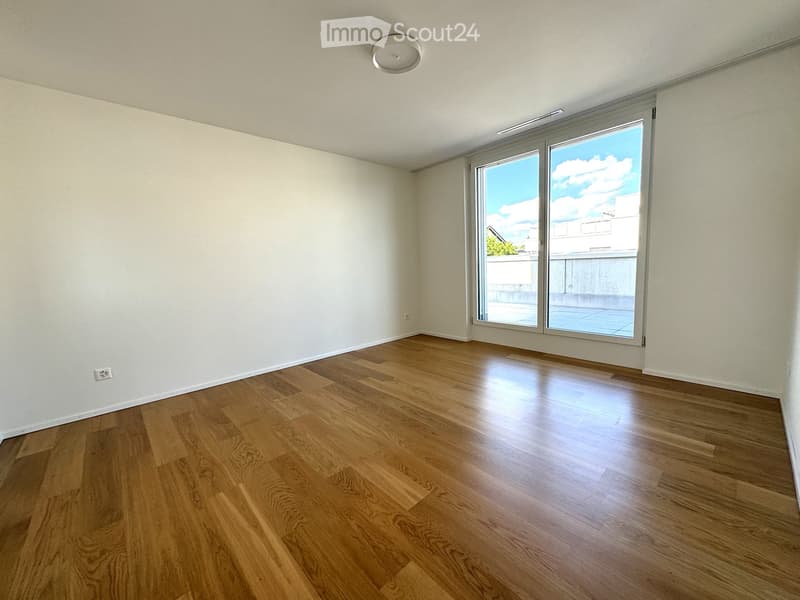 Empty room with wooden flooring, white walls, and large sliding glass doors leading to a balcony.