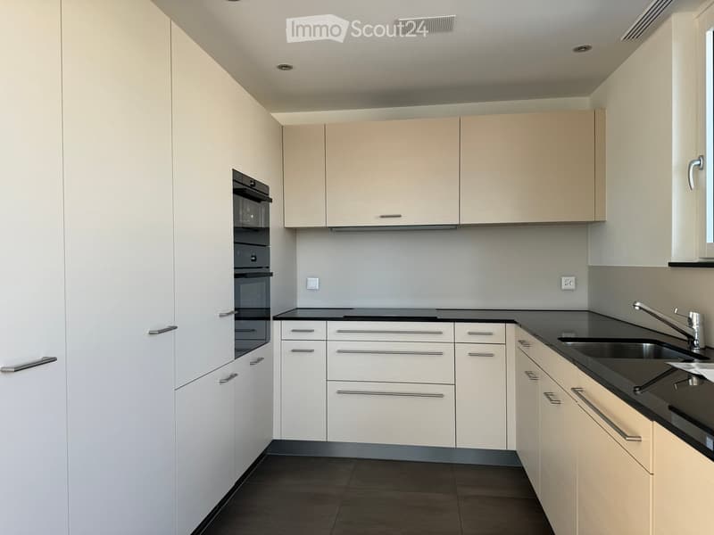 Modern kitchen with white cabinets, black countertops, and stainless steel fixtures.