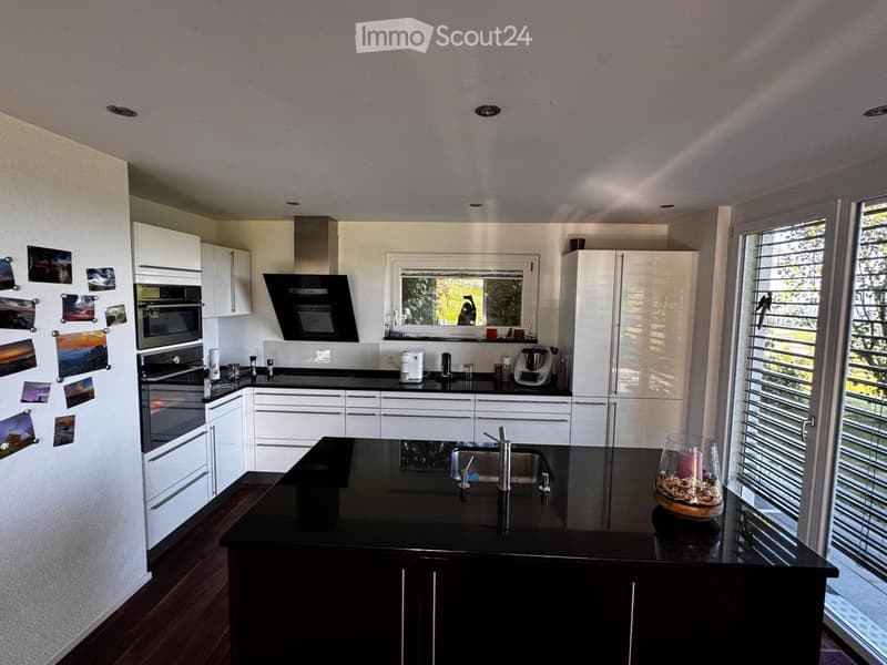 Modern kitchen with white cabinets, black countertops, stainless steel appliances, and a large island with a sink and faucet.