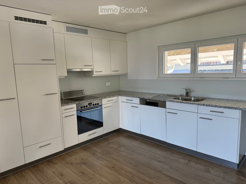 Modern kitchen with white cabinets, granite countertops, stainless steel appliances, and wooden flooring.