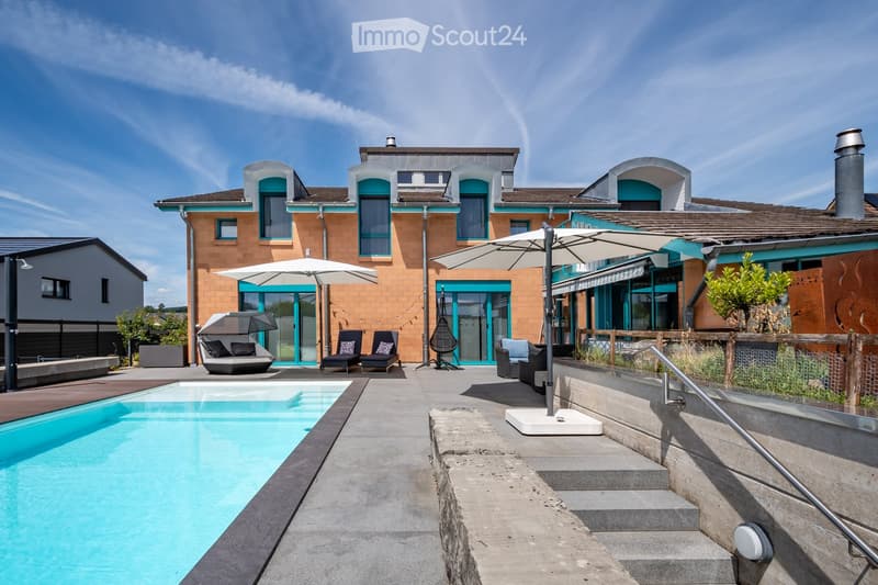 Modern outdoor area with a swimming pool, lounge chairs, umbrellas, and a stylish house in the background.