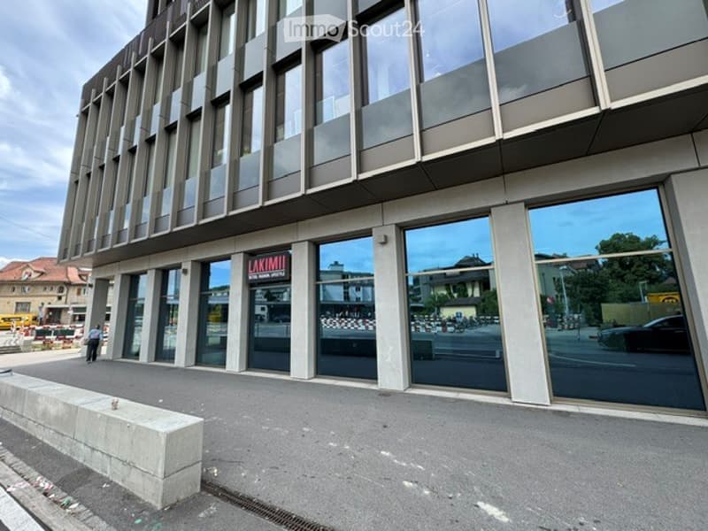 Modern multi-story building with large glass windows and a sleek, contemporary design. The ground floor features a storefront with signage reading "LAKIMI."