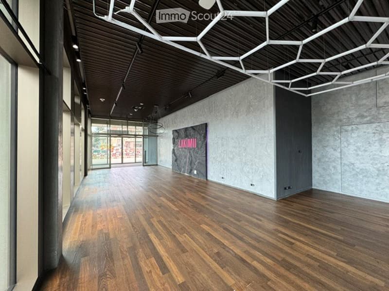 Empty hallway with wooden flooring, modern ceiling design, and large windows at the end.