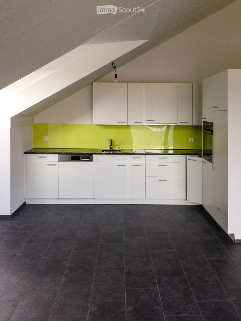 Modern kitchen with white cabinets, black countertops, and a green backsplash. Features a sink, faucet, and dishwasher.