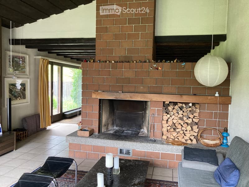 Living room with a brick fireplace, sofa, coffee table, and decorative items.